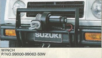Winch 99000-99062-50W: барабан, трос и крюк перед решёткой Suzuki, внутри чёрного ограждения